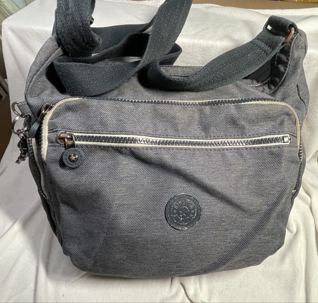 Kipling Grey Denim Shoulder Bag with Monkey Charm (Category: Shoulder Bags) located in Mandaluyong City. Submitted by coolmeybab (Listing ID 1461822120, Image 1). Description: - Grey Kipling shoulder bag - Durable denim-like material - Multiple zippered pockets on the front - Spacious interior with an additional zippered pocket - Includes the iconic Kipling monkey charm - Adjustable strap for customized comfort.