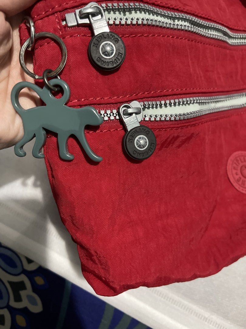 Kipling Red Nylon Crossbody Bag with Monkey Charm (Category: Cross-body Bags) located in Manila. Submitted by edensy (Listing ID 1461934360, Image 2). Description: - Authentic Kipling crossbody bag - Durable nylon material - Multiple zippered compartments on the front - Includes signature Kipling monkey charm - Light grey interior lining - Interior zippered pocket - Adjustable strap for comfortable wear - Ideal for everyday use.