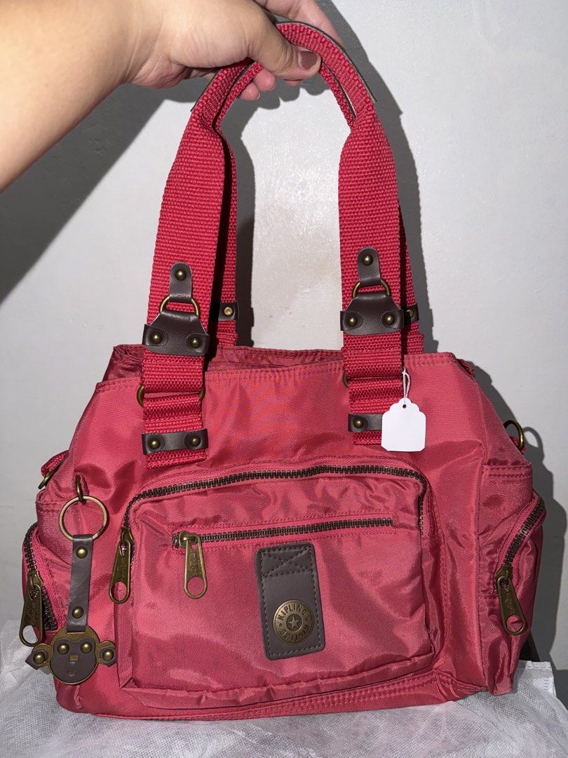 Kipling Red Nylon Shoulder Bag with Multiple Pockets (Category: Shoulder Bags) located in Manila. Submitted by frescyann14 (Listing ID 1461885018, Image 1). Description: - Red Kipling shoulder bag - Durable nylon material - Multiple interior and exterior pockets for organization - Secure zipper closures - Adjustable shoulder straps - Approximately 13 inches wide - Ideal for everyday use - Comes with a cute monkey keychain charm.