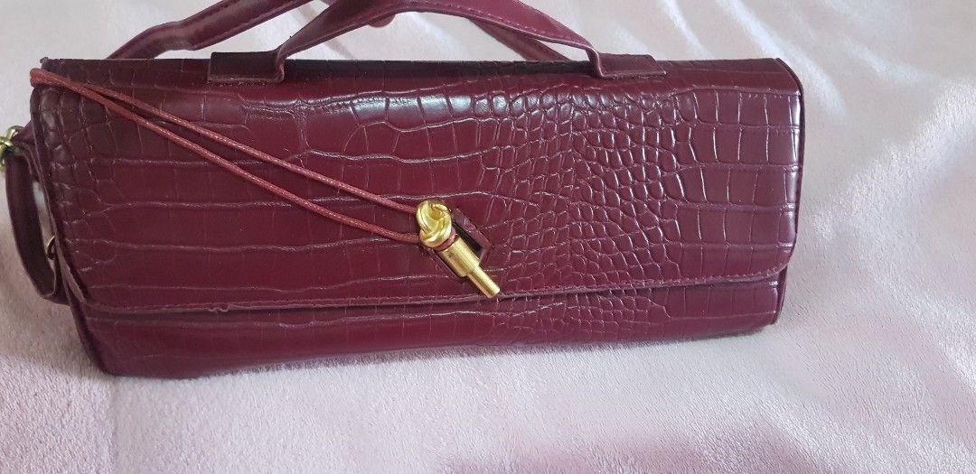 Maroon Crocodile Embossed Clutch Bag with Strap (Category: Clutches) located in Quezon City. Submitted by seventeenjeonghan (Listing ID 1461808098, Image 1). Description: - Elegant maroon clutch bag - Crocodile embossed texture - Convenient top handle - Detachable long strap for versatility - Stylish gold hardware on front closure - Lined with dark green material - Ideal for evening wear and special occasions.