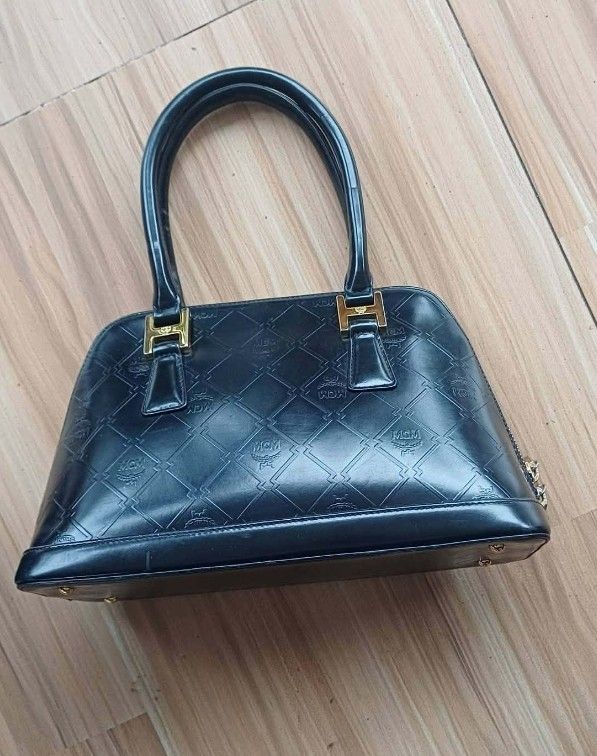 MCM Black Monogrammed Leather Dome Handbag (Category: Luxury Bags & Wallets) located in Manila. Submitted by boldfire_315559 (Listing ID 1461839335, Image 3). Description: - Classic black MCM dome handbag - Signature MCM monogram pattern embossed all over - Gold hardware details - Zipper closure - Interior MCM lining with a small zip pocket - Versatile for everyday or special occasions - A timeless MCM piece.