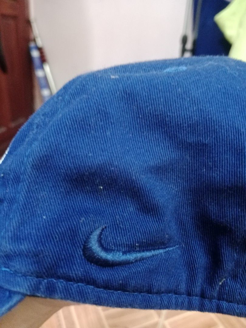 Nike Blue Strapback Cap (Category: Caps & Hats) located in Naga. Submitted by thrift.vincent (Listing ID 1461850437, Image 2). Description: Blue six-panel strapback cap with large embroidered NIKE text on the front in black with a white outline. Tonal blue embroidered eyelets and matching blue top button. Curved brim. Strapback closure at the back. No visible wear.