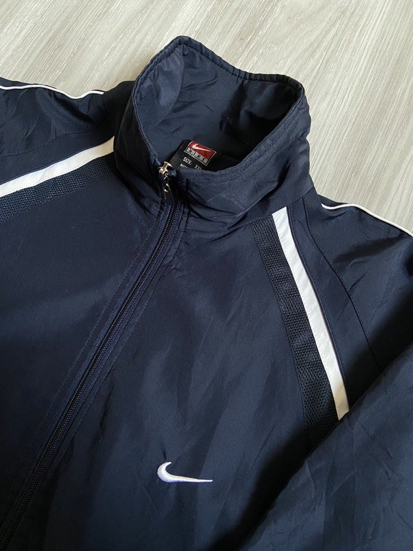 Nike Navy Blue Track Jacket with White Stripes (Category: Coats, Jackets and Outerwear) located in Cavite. Submitted by hail1530 (Listing ID 1461876963, Image 2). Description: - Classic Nike track jacket - Navy blue with white stripe detailing on shoulders and sleeves - Full zip closure - Stand-up collar - Elasticated cuffs and hem - Ideal for casual wear or light workouts.