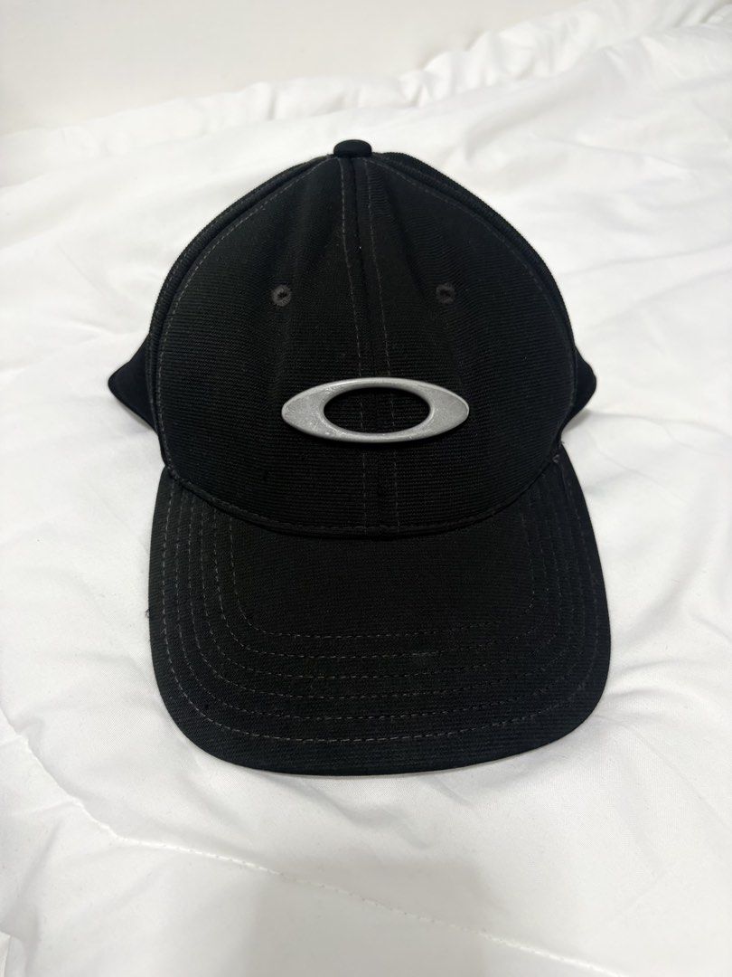 Oakley Black Metal Eclipse Cap (Category: Caps & Hats) located in Manila. Submitted by weararchive.mnl (Listing ID 1461877851, Image 1). Description: Oakley Black Metal Ellipse Cap 🧢 FIXED PRICE Preloved, good condition 🖤 • Authentic Oakley stretch-fit design • Raised metallic silver Ellipse logo on front • Oakley A-Flex fitted stretch band • Size: L/XL • Clean black colorway, versatile streetwear look.