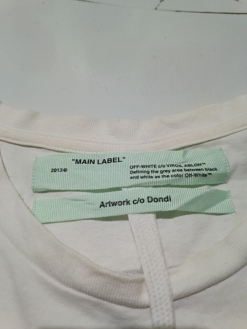 OFF-WHITE c/o VIRGIL ABLOH "MAIN LABEL" Dondi Tee (Category: Tshirts & Polo Shirts ) located in Barotac Nuevo. Submitted by gray101 (Listing ID 1461972510, Image 3). Description: - Authentic Off-White x Dondi collaboration t-shirt - Color: White - Material: Cotton - Features graphic print on front and back - "MAIN LABEL" and "Artwork c/o Dondi" tags included - Size: XXL - Perfect for collectors.