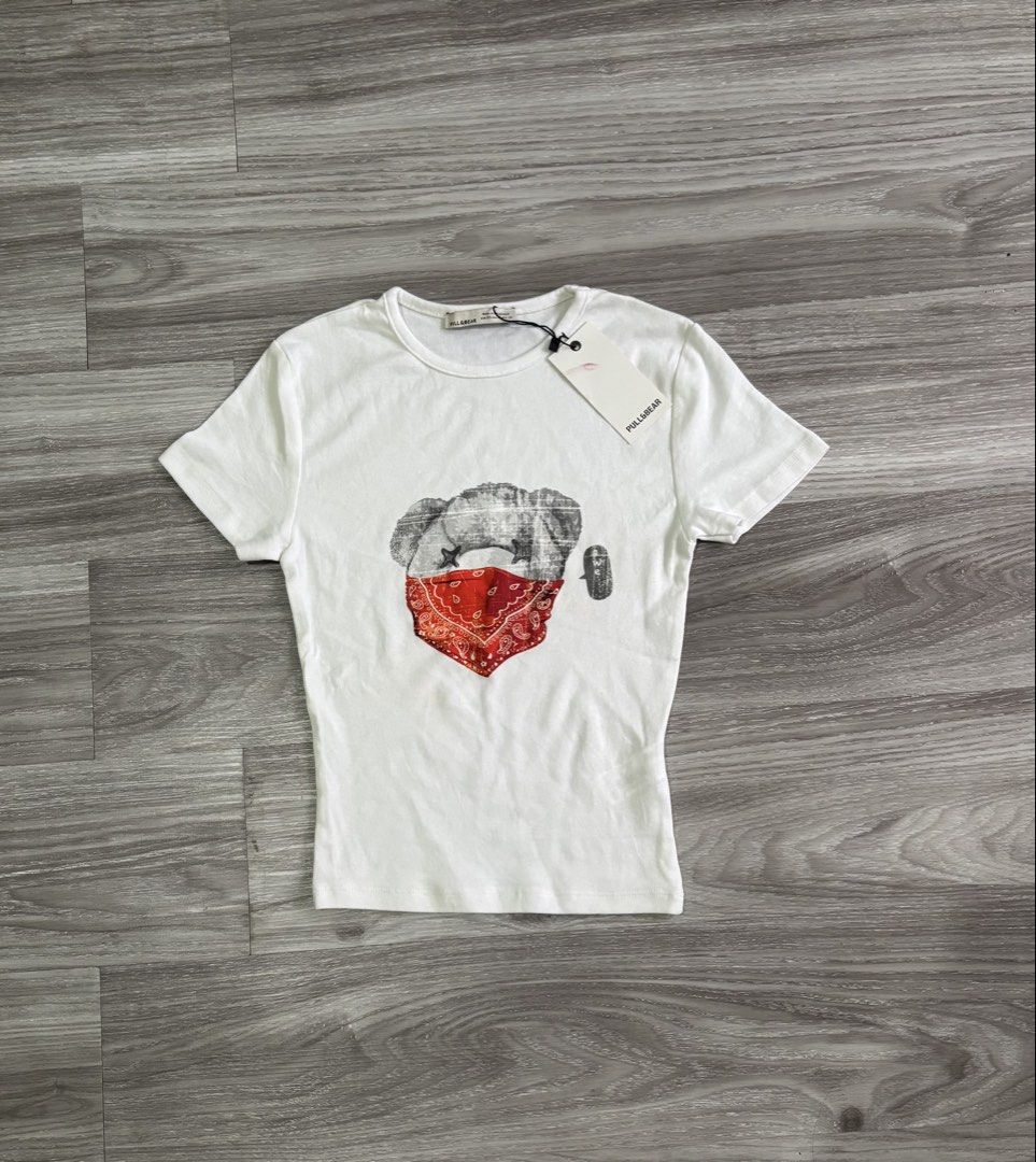 Pull&Bear White T-shirt with Bear Graphic (Category: Shirts) located in Tayabas. Submitted by declutterwithmeee29 (Listing ID 1461860637, Image 1). Description: - Brand: Pull&Bear - Size: Approximately S - Design: Cool graphic of a bear wearing a red bandana - Material: Soft and comfortable - Style: Great for casual wear.