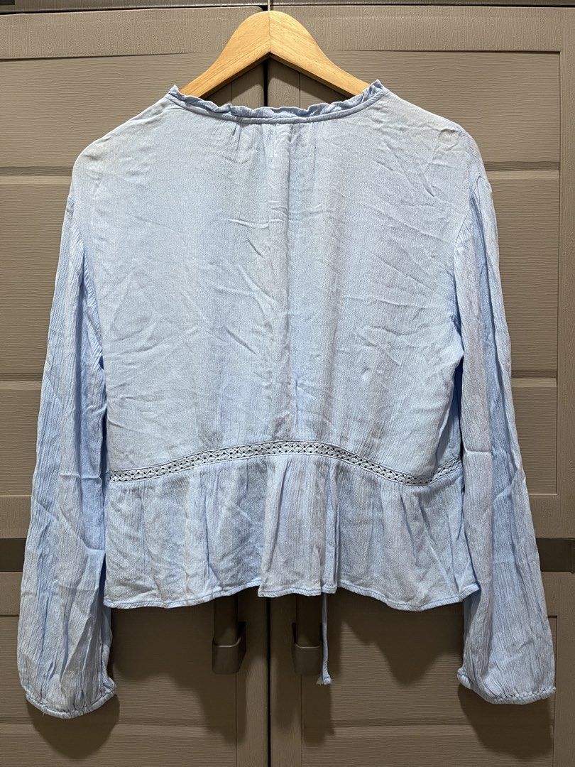 Stradivarious Light Blue Textured Long Sleeve Blouse Size L (Category: Longsleeves) located in Koronadal. Submitted by declutterprelovednitine_ey (Listing ID 1461810607, Image 2). Description: - Light blue textured blouse from Bershka - Long sleeves with delicate lace detail - Button-up front with adjustable tie at the hem - Minor flaw: small hole on the left sleeve near the cuff (refer to the last photo for exact location).