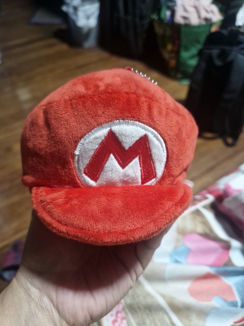 Super Mario Plush Coin Pouch Keychain Red (Category: Character Goods) located in Manila. Submitted by veelafiera (Listing ID 1461946336, Image 1). Description: - Officially licensed Nintendo Mario hat plush coin pouch. - Features the iconic 'M' logo. - Zipper closure for secure storage. - Compact size, ideal for attaching to bags or keys. - Perfect for holding coins, earbuds, or other small essentials..