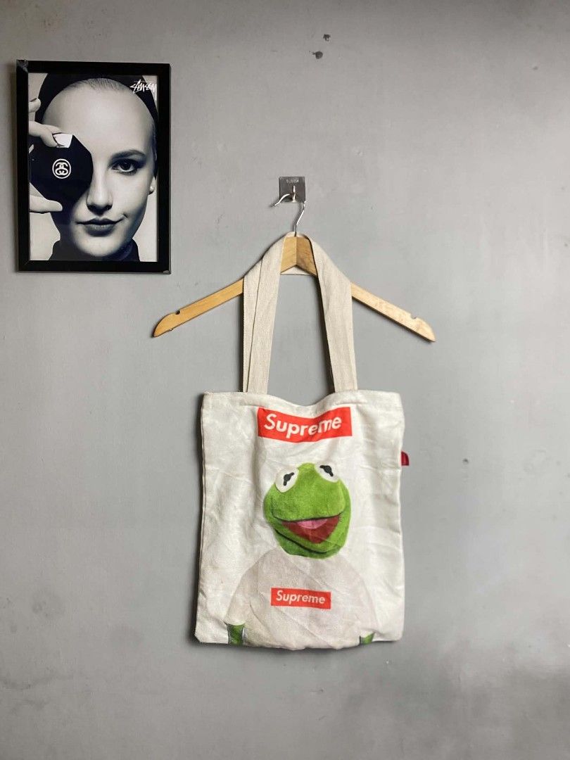 Supreme Kermit the Frog Tote Bag (Category: Sling Bags) located in Manila. Submitted by arjay_cuayzon2 (Listing ID 1461950895, Image 1). Description: - White canvas tote bag with Kermit the Frog graphic - Features two Supreme box logos - Magnetic snap closure - Minor stains visible on fabric - Ideal for everyday use.