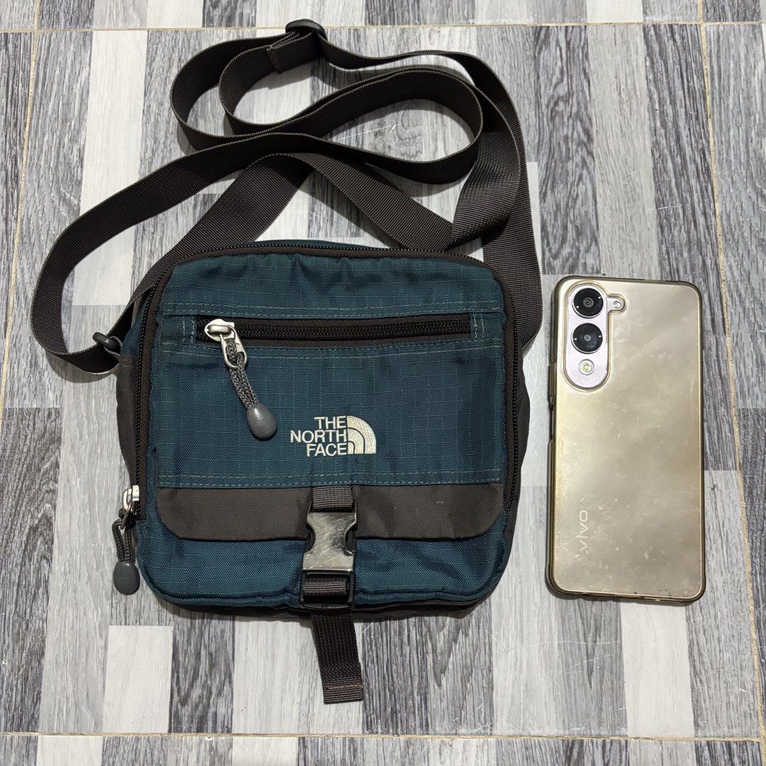 The North Face Small Crossbody Bag Teal (Category: Cross-body Bags) located in Banga. Submitted by akosiloco (Listing ID 1461920344, Image 1). Description: - Brand: The North Face - Color: Teal - Style: Crossbody bag - Main compartment with internal pockets - Front zip pocket for quick access - Adjustable strap for comfortable wear - Secure buckle closure on front flap - Ideal for everyday use or travel - Fits phone and other essentials.