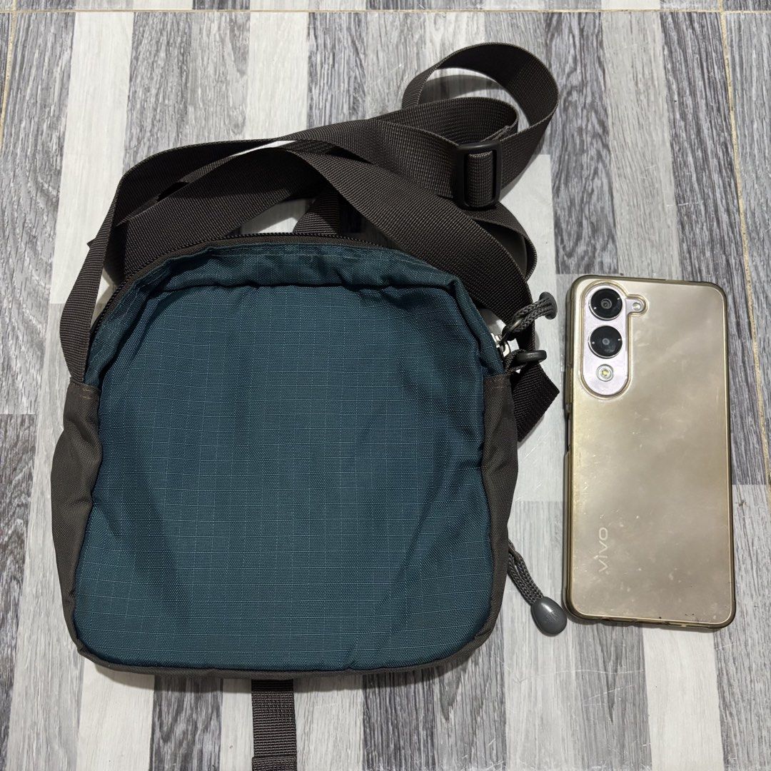 The North Face Small Crossbody Bag Teal (Category: Cross-body Bags) located in Banga. Submitted by akosiloco (Listing ID 1461920344, Image 2). Description: - Brand: The North Face - Color: Teal - Style: Crossbody bag - Main compartment with internal pockets - Front zip pocket for quick access - Adjustable strap for comfortable wear - Secure buckle closure on front flap - Ideal for everyday use or travel - Fits phone and other essentials.