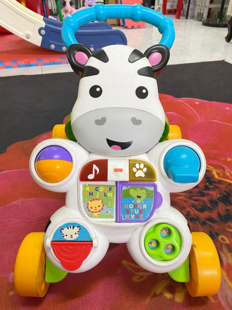 Walker (Category: Infant Playtime) located in Cyberjaya. Submitted by pijaisa2908 (Listing ID 1461921892, Image 3). Description: - Baby walker designed to aid first steps and encourage play. - Features a wooden activity station with farm-themed elements: barn, animals, bead maze. - Second walker is a colorful zebra-themed activity station with interactive buttons, lights, and sounds. - Promotes motor skill development and sensory stimulation. - S
