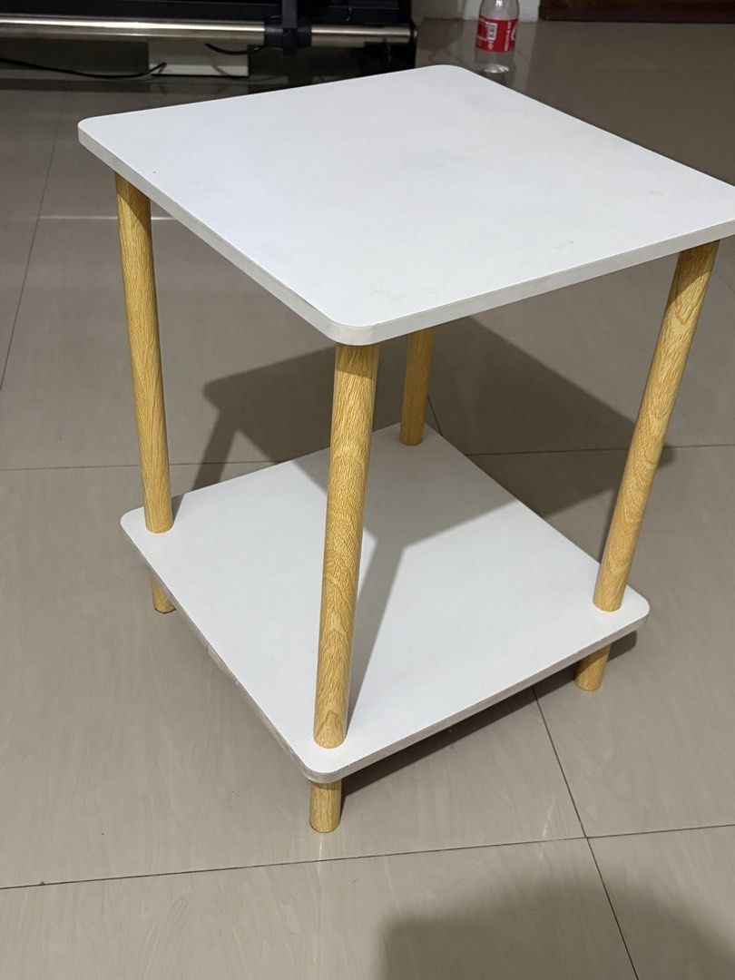 White 2-Tier Side Table with Wooden Legs (bed side table) (Category: Tables & Sets) located in Manila. Submitted by lizgee_ (Listing ID 1461835514, Image 1). Description: - Modern 2-tier side table - White top and shelf - Natural wood legs - Ideal for living room or bedroom - Easy to assemble - Compact size fits most spaces - Perfect for books, drinks, or a lamp.
