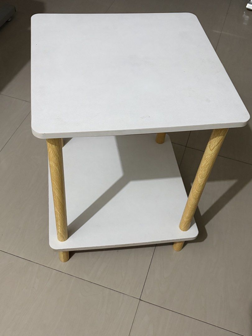 White 2-Tier Side Table with Wooden Legs (bed side table) (Category: Tables & Sets) located in Manila. Submitted by lizgee_ (Listing ID 1461835514, Image 2). Description: - Modern 2-tier side table - White top and shelf - Natural wood legs - Ideal for living room or bedroom - Easy to assemble - Compact size fits most spaces - Perfect for books, drinks, or a lamp.