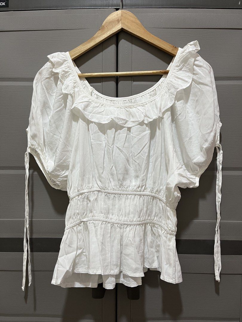 White Ruffled Puff Sleeve Smocked Peplum Top (Category: Blouses) located in Koronadal. Submitted by declutterprelovednitine_ey (Listing ID 1461810405, Image 2). Description: - Adorable white top with charming ruffle neckline. - Features stylish puff sleeves with tie details. - Flattering peplum silhouette to the smocked waist. - Made from lightweight fabric, ideal for hot weather. - Versatile piece: easily pairs with jeans or skirts..