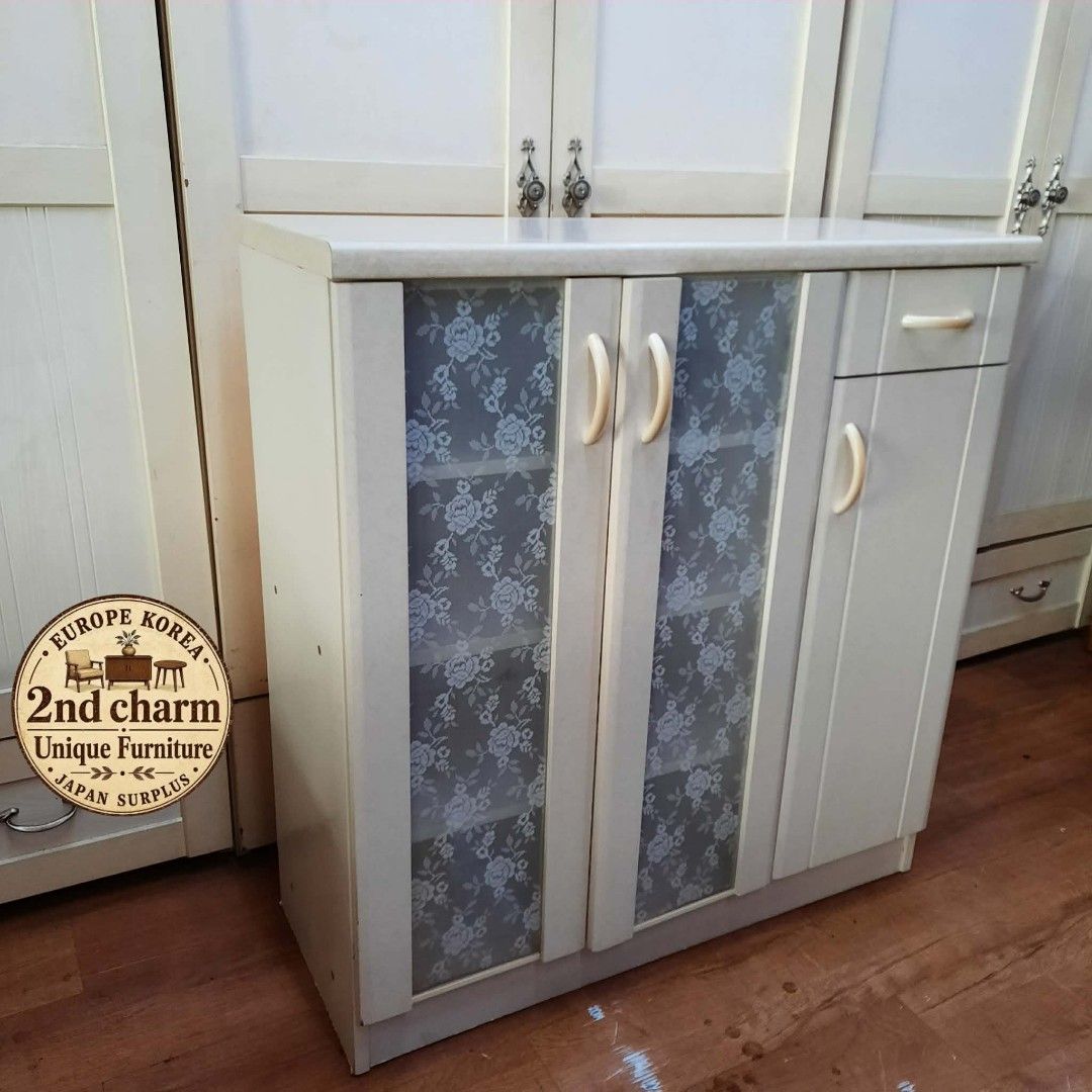 White Storage Cabinet with Glass Doors and Drawer (Category: Shelves, Cabinets & Racks) located in Manila. Submitted by ivan_furnitures421 (Listing ID 1461897663, Image 2). Description: - Elegant white storage cabinet - Features two glass doors with a beautiful floral lace pattern on the left - One door with an integrated drawer on the right - Offers generous shelf space for organized storage - Ideal for use in the kitchen or living room - Compac