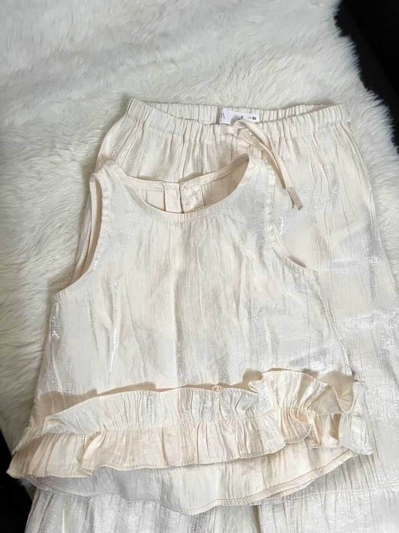 Zara Satin Ruffle coords (Category: Babies & Kids Fashion) located in Quezon City. Submitted by raidmystyle (Listing ID 1461853265, Image 2). Description: - Adorable Zara cream set for kids. - Includes a sleeveless top with a ruffled hem. - Matching culottes with an elastic waistband for comfort. - Both pieces feature a subtle metallic thread detail. - Perfect for parties and special occasions..