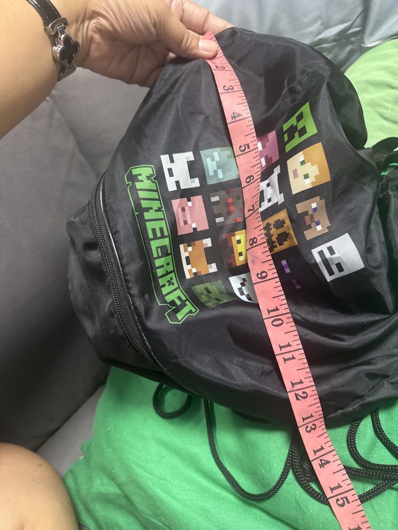 2027 Minecraft Drawstring Bag with Zippered Bottom (Category: Backpacks) located in Silang. Submitted by sari2bilina (Listing ID 1462145592, Image 3). Description: - Black drawstring bag with a fun Minecraft character print. - Features a main compartment that closes with a drawstring. - Includes a convenient zippered compartment at the bottom for extra storage. - Ideal for gym, school, or travel. - Measures approximately 15 inches tall. - A fanta