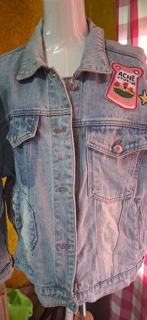 Acne Studios Denim Jacket with Embroidered Back (Category: Coats, Jackets and Outerwear) located in Manila. Submitted by katkween23 (Listing ID 1462065454, Image 3). Description: - Light wash denim jacket - Embroidered 'Solemnity' graphic on the back - Cute 'Acne Studios' patch on the front pocket - Distressed details on pockets and hem - Button-up front with chest pockets - Ideal for layering.