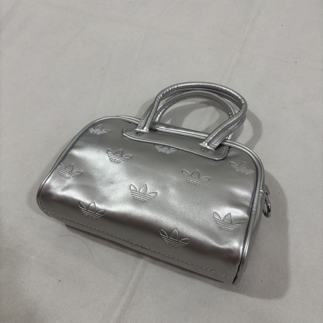 Adidas Silver Embossed Trefoil Mini Y2K Bowling Bag (Category: Purses & Pouches) located in Cavite. Submitted by itsayaaa (Listing ID 1462093255, Image 2). Description: - Stylish silver Adidas mini bowling bag - All-over embossed trefoil logo pattern - Versatile with top handles and a detachable shoulder strap - Practical black interior with a zip closure - Ideal size for carrying your daily essentials Y2K style.