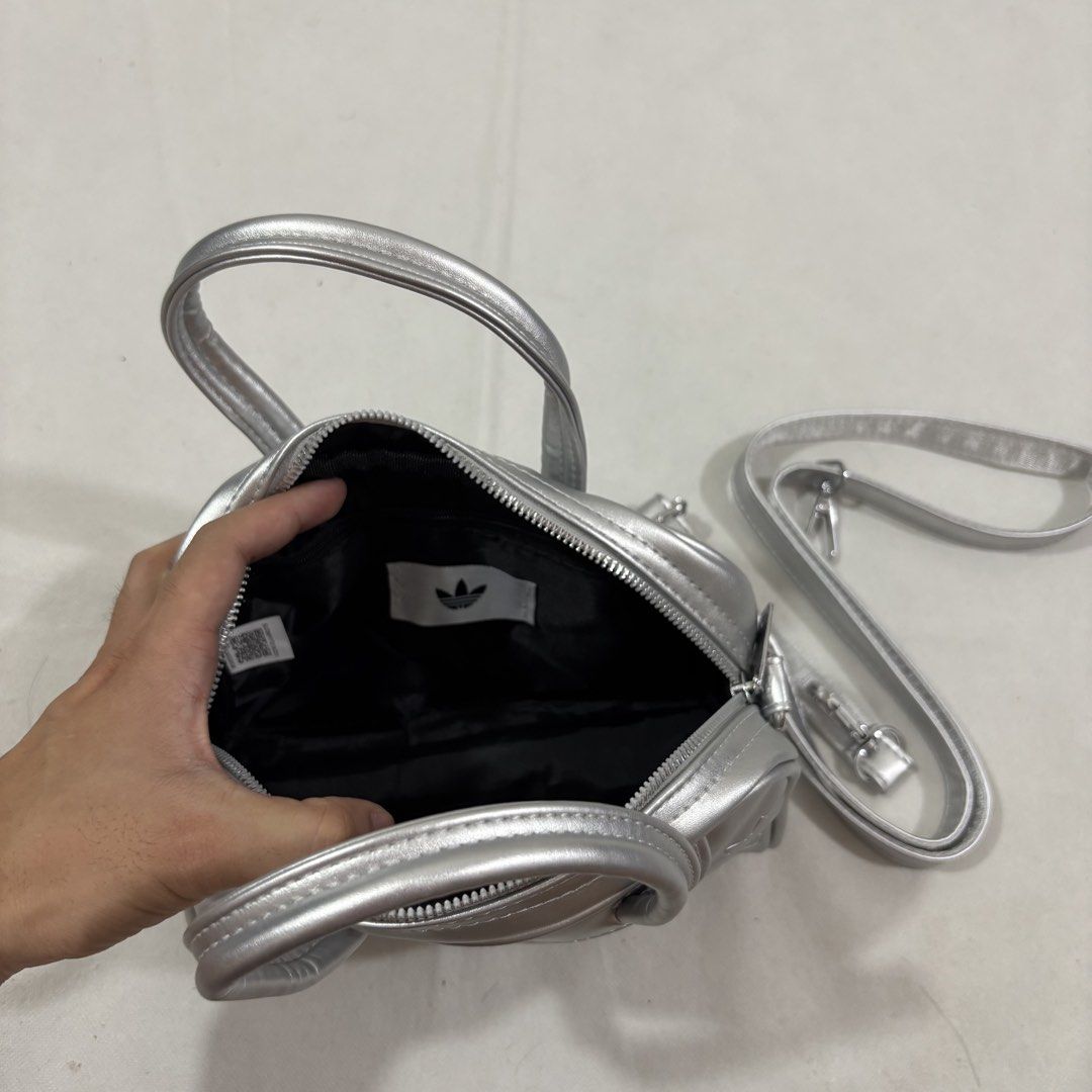 Adidas Silver Embossed Trefoil Mini Y2K Bowling Bag (Category: Purses & Pouches) located in Cavite. Submitted by itsayaaa (Listing ID 1462093255, Image 3). Description: - Stylish silver Adidas mini bowling bag - All-over embossed trefoil logo pattern - Versatile with top handles and a detachable shoulder strap - Practical black interior with a zip closure - Ideal size for carrying your daily essentials Y2K style.