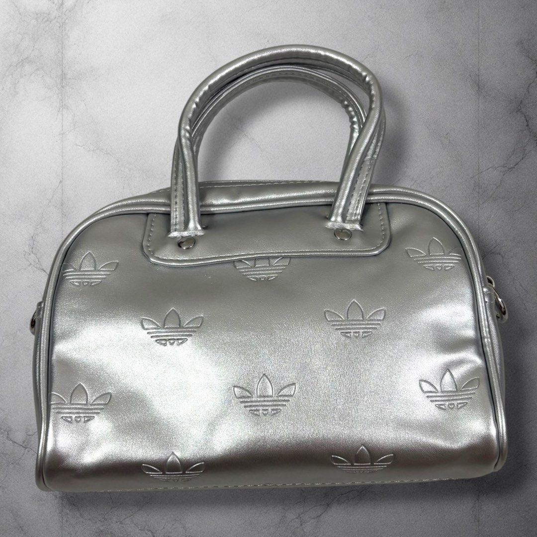 Adidas Silver Embossed Trefoil Mini Y2K Bowling Bag (Category: Purses & Pouches) located in Cavite. Submitted by itsayaaa (Listing ID 1462093255, Image 1). Description: - Stylish silver Adidas mini bowling bag - All-over embossed trefoil logo pattern - Versatile with top handles and a detachable shoulder strap - Practical black interior with a zip closure - Ideal size for carrying your daily essentials Y2K style.