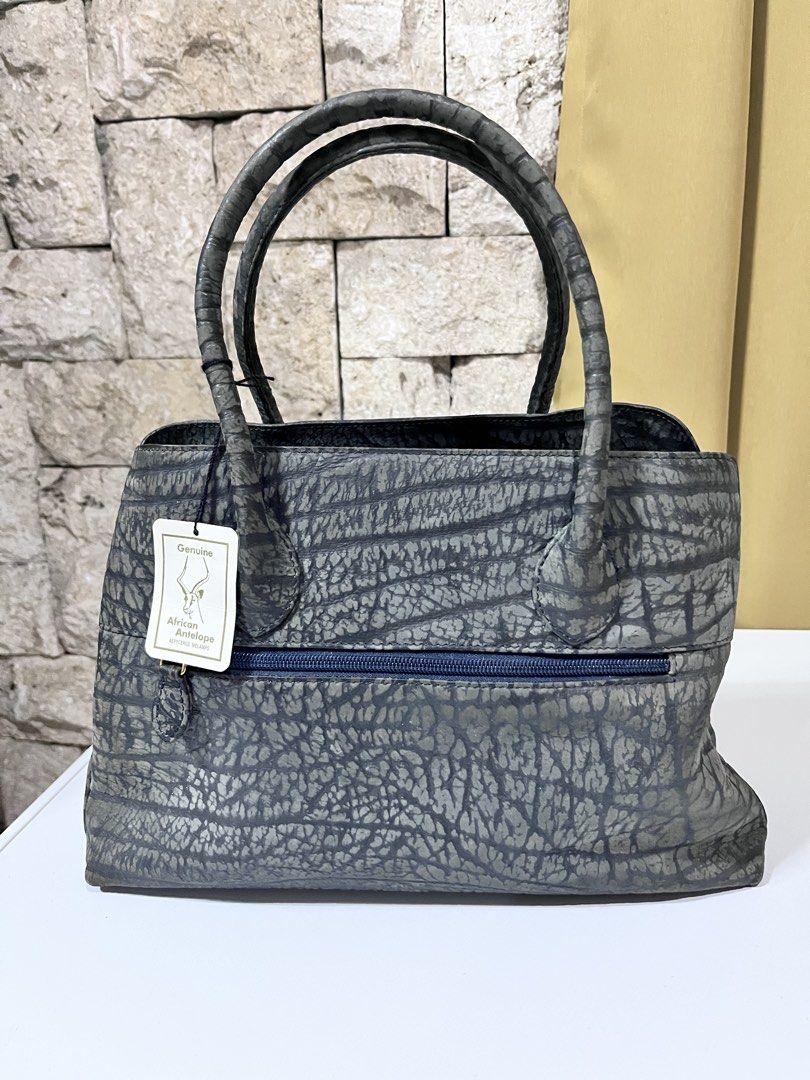 African Antelope leather Handbag (Category: Tote Bags) located in Nagcarlan. Submitted by prelovedbymayen (Listing ID 1462102858, Image 2). Description: Gray African Antelope leather handbag. Design Details Texture Details: The deep, horizontal, furrowed lines running across the body are highly characteristic of antelope (shibo) leather. The lower corners show a tighter, micro-pebbled grain pattern, highlighting the natural variance of the authen