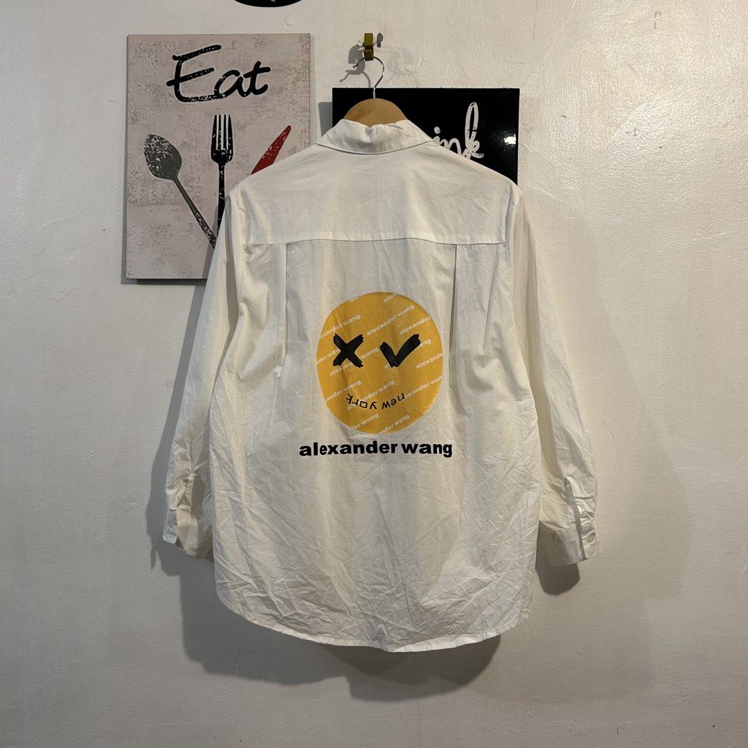 Alexander Wang White Rhinestone Logo Button Up Shirt (Category: Tshirts & Polo Shirts ) located in Manila. Submitted by jakes_thrift_shop (Listing ID 1462036730, Image 2). Description: - Alexander Wang white button-up shirt - Features a sparkling rhinestone logo on the front - Eye-catching graphic smiley face print on the back - Made from comfortable and breathable 100% cotton - Versatile for both casual outings and making a fashion statement.
