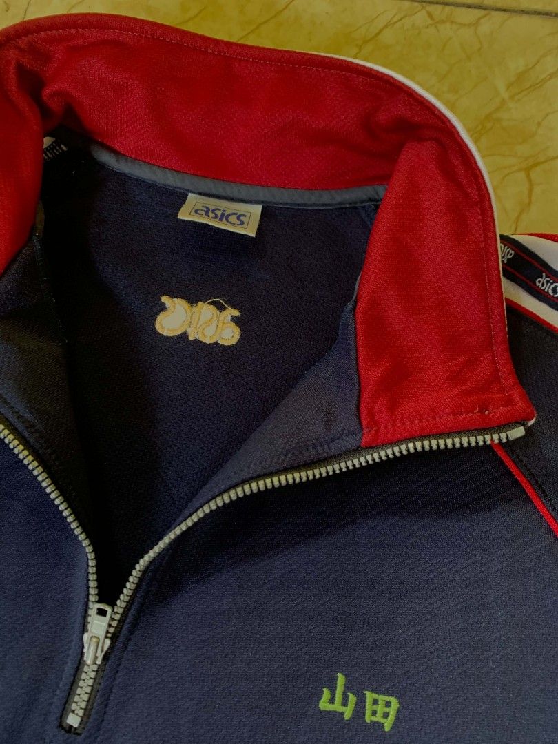 Asics Navy Blue Track Jacket with Red Collar (Category: Coats, Jackets and Outerwear) located in Quezon City. Submitted by chic.on.a.dime (Listing ID 1462066855, Image 3). Description: - NO ISSUE - Navy blue Asics track jacket - Features a red collar - White and red striped accents on sleeves - Quarter zip closure - Two front pockets - Asics logo prominently displayed on the back - Ideal for athletic activities or everyday casual styling - Large 