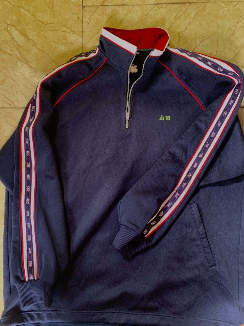 Asics Navy Blue Track Jacket with Red Collar (Category: Coats, Jackets and Outerwear) located in Quezon City. Submitted by chic.on.a.dime (Listing ID 1462066855, Image 2). Description: - NO ISSUE - Navy blue Asics track jacket - Features a red collar - White and red striped accents on sleeves - Quarter zip closure - Two front pockets - Asics logo prominently displayed on the back - Ideal for athletic activities or everyday casual styling - Large 