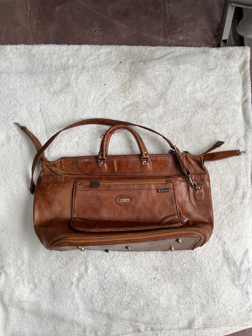 Avis leather big travel bag (Category: Backpacks) located in General Trias. Submitted by zrchustle.604 (Listing ID 1462180528, Image 1). Description: Avis travel bag, crafted from rich, vegetable-tanned brown leather. This piece features a classic structured silhouette reminiscent of traditional multi-compartment travel briefcases and duffels. It is accented by dual zippered front pockets, prominent stitched detailing, and two central metal logo 