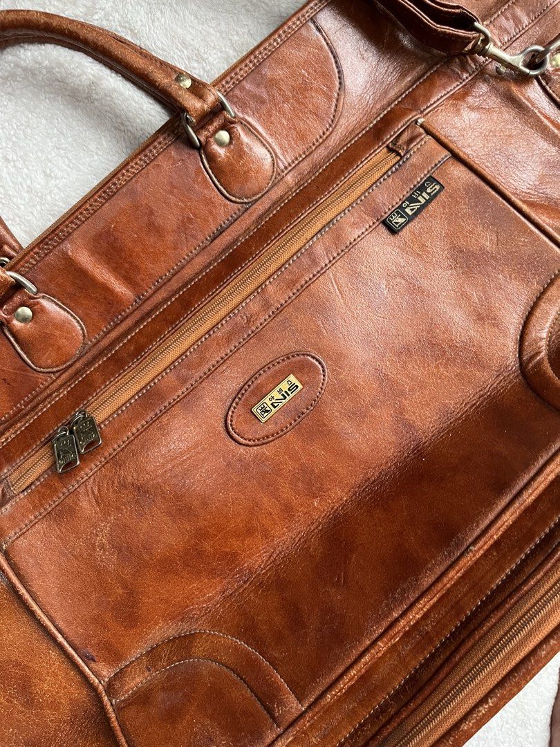 Avis leather big travel bag (Category: Backpacks) located in General Trias. Submitted by zrchustle.604 (Listing ID 1462180528, Image 2). Description: Avis travel bag, crafted from rich, vegetable-tanned brown leather. This piece features a classic structured silhouette reminiscent of traditional multi-compartment travel briefcases and duffels. It is accented by dual zippered front pockets, prominent stitched detailing, and two central metal logo 