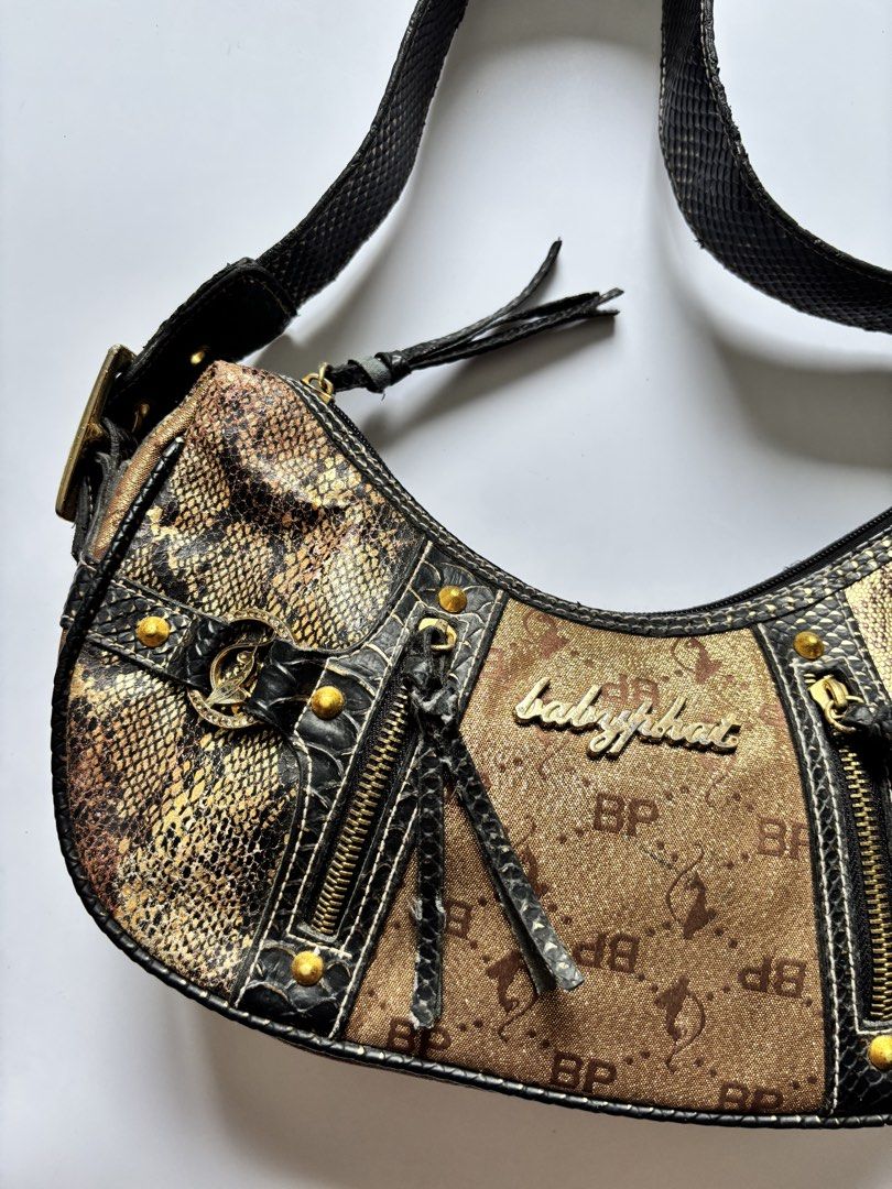 Baby Phat y2k Bag (Category: Shoulder Bags) located in Manila. Submitted by anik.anik_ph (Listing ID 1462089601, Image 2). Description: - Cute shoulder bag with snakeskin and monogram print. - Stylish gold hardware details. - Convenient front zipper pockets. - Black strap with snakeskin texture. - Ideal for everyday use. - Shows some signs of wear, but plenty of life left. Y2k Baby Phat shoulder bag W 13 inches L 8 inches Grab ₱5000 This is a vin