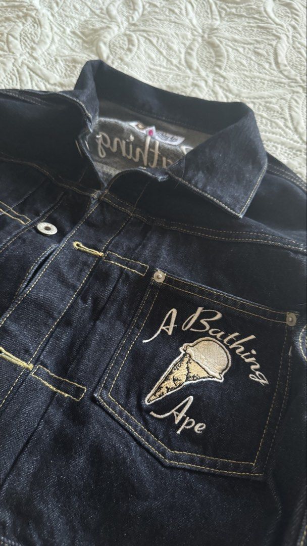 BAPE Denim Jacket Ice Cream Patch (Category: Coats, Jackets and Outerwear) located in Paranaque City. Submitted by sierraah (Listing ID 1462220244, Image 2). Description: - Brand: A Bathing Ape (BAPE) - Style: Blue Denim Jacket - Size: XS on tag -Bought in: Osaka, Japan -Never been used/worn - Features: Embroidered ice cream cone and logo on chest pocket - Back Detail: "A Bathing Ape" embroidery across the back - Closure: Button front and button 
