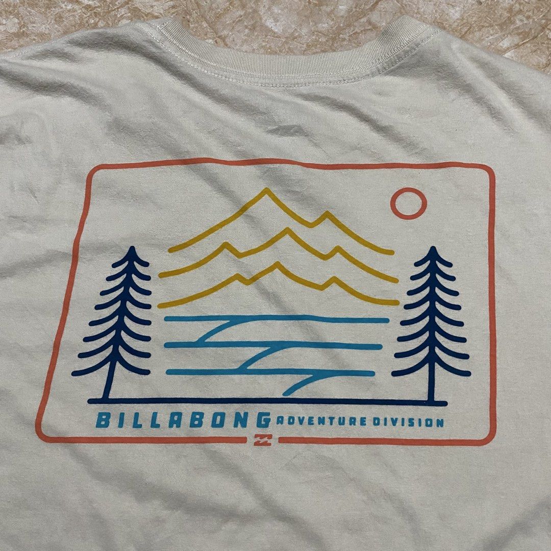 Billabong Adventure Division Tee (Category: Activewear) located in Manila. Submitted by killthismane (Listing ID 1462138183, Image 1). Description: A cream-colored Billabong Adventure Division short-sleeve t-shirt featuring a mountain, ocean, and tree graphic on the back..