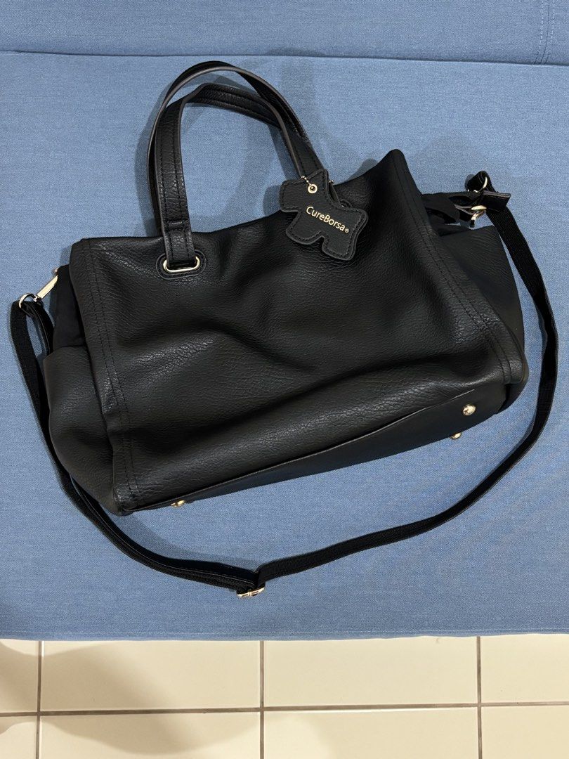 Black Leather Tote Bag (Category: Shoulder Bags) located in Pasig City. Submitted by sarpaz (Listing ID 1462073107, Image 1). Description: - Brand: CureBorsa - Material: Black Leather - Features: Top handles, detachable shoulder strap - Hardware: Gold details (bottom studs, strap attachments) - Interior: Zippered compartment, spacious main compartment - Ideal for: Everyday use Bought in JAPAN.