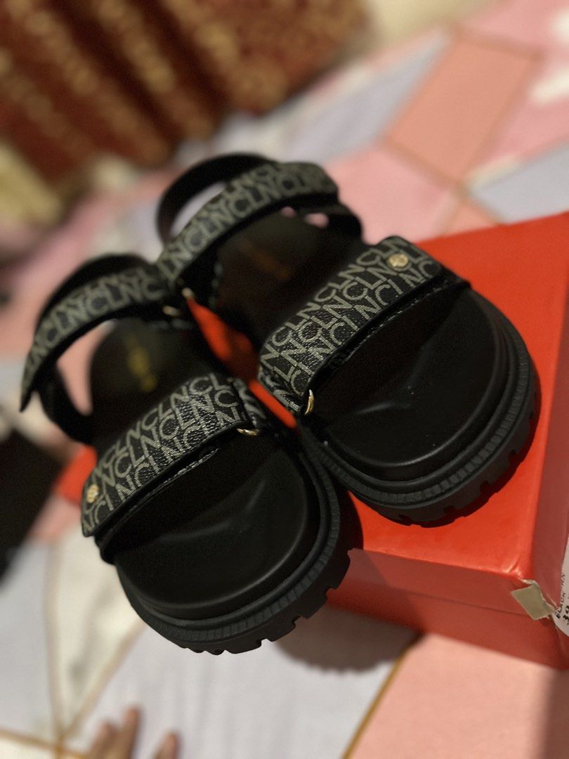 Black Sandals with Monogram Straps (Category: Flats & Sandals) located in Guiguinto. Submitted by marinelcru86104 (Listing ID 1462197692, Image 2). Description: - Stylish black sandals with a repeating monogram pattern on the straps. - Features a comfortable chunky sole for all-day wear. - Adjustable velcro closures for a perfect fit. - Includes the original box. - Ideal for casual outings and everyday comfort..