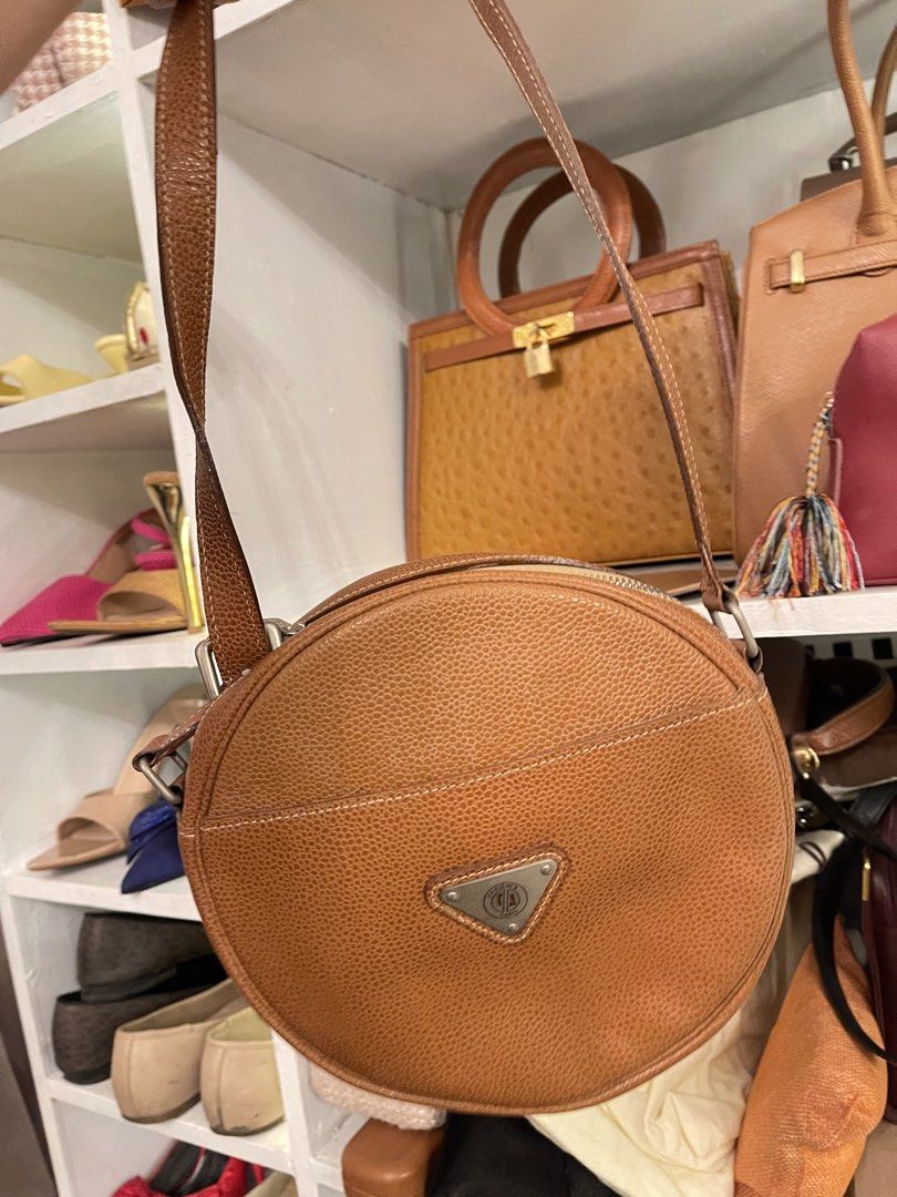 Brown Leather Round Handbag (Category: Purses & Pouches) located in Marilao. Submitted by wardrovearchives (Listing ID 1462203957, Image 2). Description: - Cute round brown leather bag - Pebbled leather texture - Single top handle - Adjustable long strap - Triangular metal emblem on front - Spacious interior for essentials - Great for everyday use.