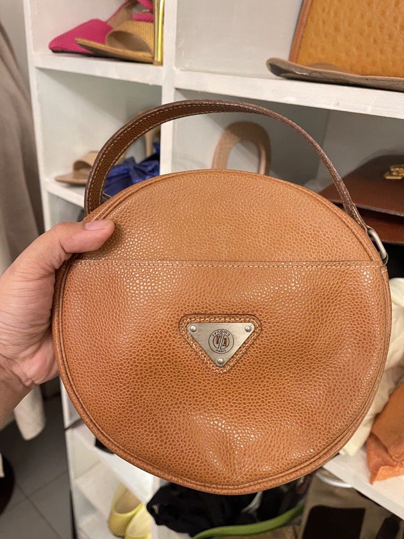 Brown Leather Round Handbag (Category: Purses & Pouches) located in Marilao. Submitted by wardrovearchives (Listing ID 1462203957, Image 1). Description: - Cute round brown leather bag - Pebbled leather texture - Single top handle - Adjustable long strap - Triangular metal emblem on front - Spacious interior for essentials - Great for everyday use.