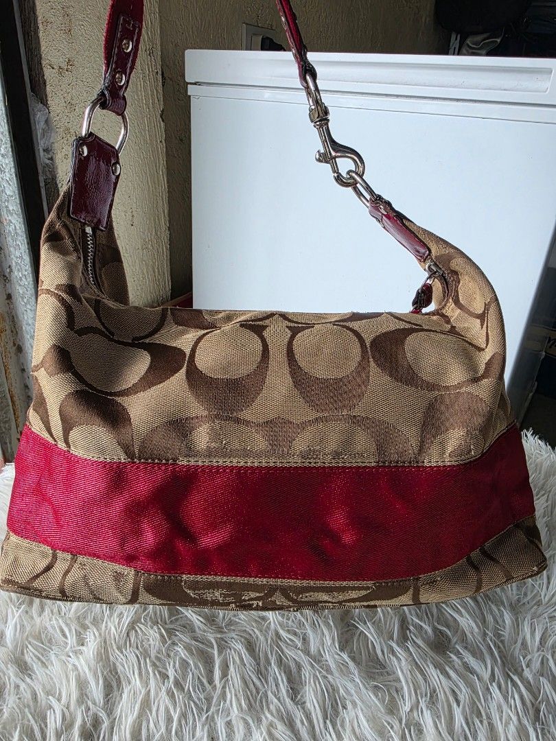 Coach Monogram Canvas Hobo Bag with Red Stripe (Category: Shoulder Bags) located in Lemery. Submitted by venus23 (Listing ID 1462107283, Image 2). Description: - Classic Coach hobo bag -Cherry charm not included - Signature monogram canvas with bold red stripe detail - Vibrant magenta interior - Secure zipper closure - Spacious main compartment - Detachable charm included.