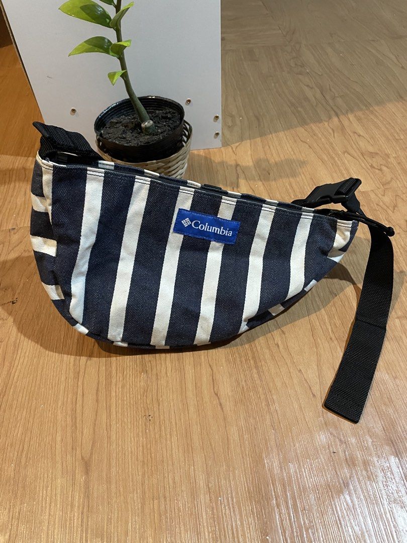 Columbia Pin Straight Bowl Bag (Category: Belt bags, Clutches and Pouches) located in Bacolod City. Submitted by maxpeynthrift (Listing ID 1462219554, Image 1). Description: UNISEX Excellent condition No issue Adjustable strap It features a distinctive crescent shape with vertical navy blue and white stripes, a prominent blue logo patch on the front, and a thick black adjustable webbed strap..