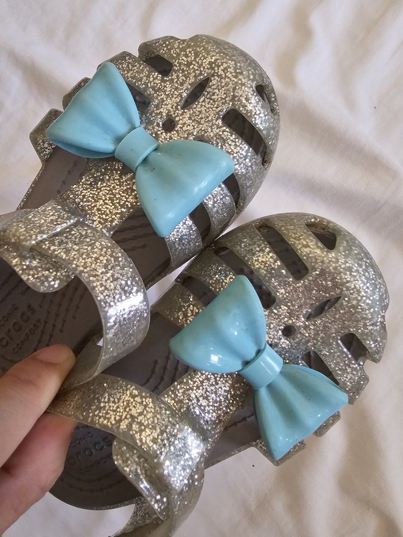 Crocs Glitter Jelly Sandals with Bows (Category: Flats & Sandals) located in Cebu City. Submitted by cutexoxoshop (Listing ID 1462189502, Image 2). Description: - Sparkly silver glitter jelly sandals by Crocs - Adorable light blue bows on the front - Easy slip-on style for kids - Soles with good grip for safety - Comfortable and fun for summer or dress-up play.