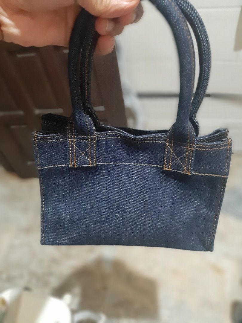 Denim Tote Bag with Red Tab Detail (Category: Tote Bags) located in Bulacan. Submitted by edisoncert71953 (Listing ID 1462053874, Image 2). Description: - Dark wash denim tote bag - Simple and sturdy construction - Small red tab detail on the side - Braided denim handles - Ideal for everyday use - Dimensions: Approx. 6 inches tall, 4 inches wide.