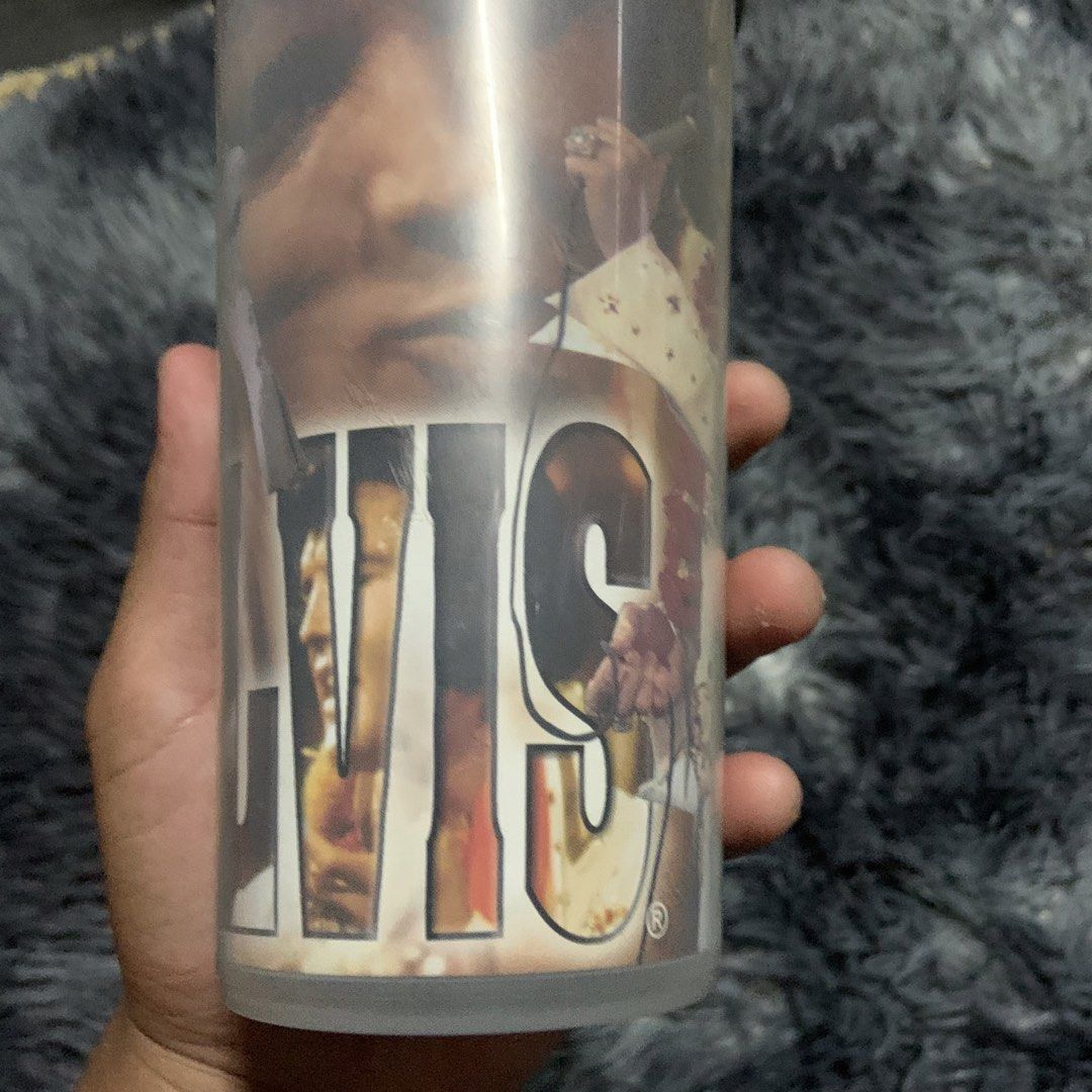 Elvis Presley Tumbler Cup (Category: Water Bottles & Tumblers) located in Compostela. Submitted by anyastark (Listing ID 1462123611, Image 3). Description: - Vintage Elvis Presley tumbler - Features iconic images of the King of Rock and Roll - Comes with a black lid - Great for any Elvis fan's collection - Ideal for your favorite beverages.