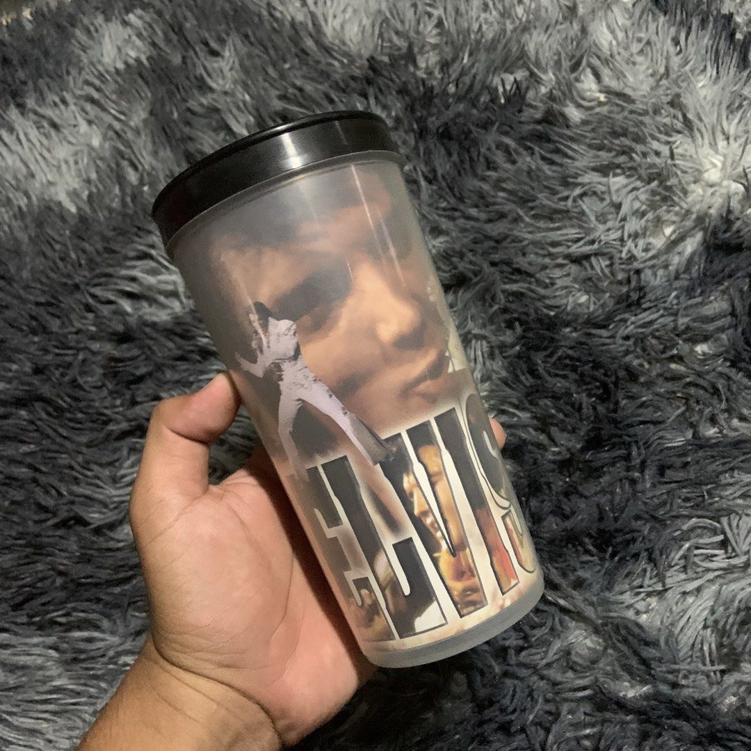Elvis Presley Tumbler Cup (Category: Water Bottles & Tumblers) located in Compostela. Submitted by anyastark (Listing ID 1462123611, Image 1). Description: - Vintage Elvis Presley tumbler - Features iconic images of the King of Rock and Roll - Comes with a black lid - Great for any Elvis fan's collection - Ideal for your favorite beverages.