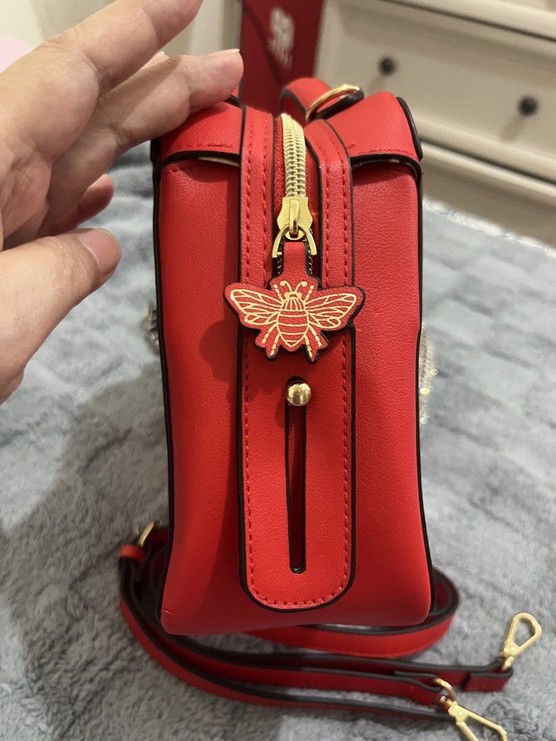 Estee Lauder Red Leather Handbag with Bee Charm (Category: Luxury Bags & Wallets) located in Mandaluyong City. Submitted by leypadilla (Listing ID 1462102363, Image 3). Description: - Genuine red leather handbag from Estee Lauder - Adorable gold bee charm on front tag - Stylish gold bee zipper pull - Includes a detachable crossbody strap for versatile wear - Immaculate and clean interior - Ideal for both daily use and special events.