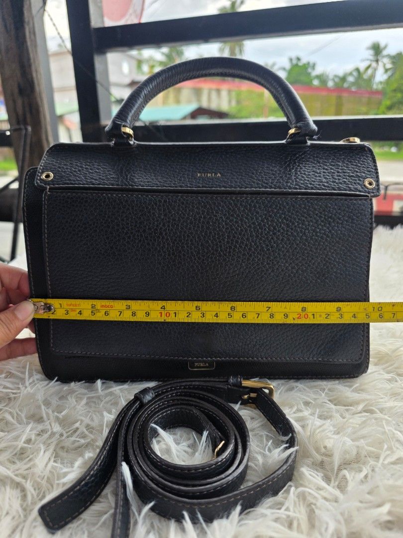 Furla Black Leather Handbag with Strap (Category: Cross-body Bags) located in Lemery. Submitted by venus23 (Listing ID 1462116905, Image 1). Description: - Brand: Furla - Material: Black pebbled leather - Features: Top handle, detachable crossbody strap - Hardware: Gold details - Interior: Clean - Dimensions: Approximately 9 inches tall - Ideal for: Everyday use.