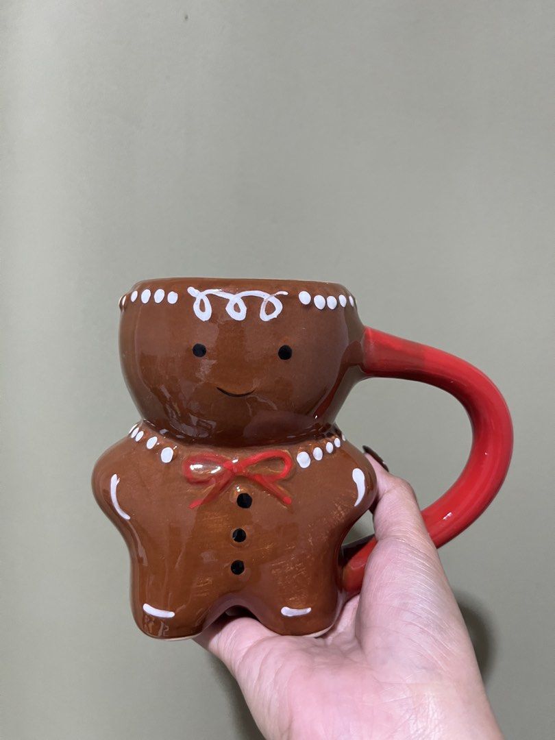 Gingerbread Man Mug with Red Handle ceramic (Category: Coffee & Tea Tableware) located in Manila. Submitted by vaughnscloset (Listing ID 1462070925, Image 1). Description: - Adorable gingerbread man design - White icing details and red bow tie/button accents - Sturdy red handle - Ideal for morning coffee or hot chocolate - Festive and unique, perfect for the holiday season - With hairline, for display only..
