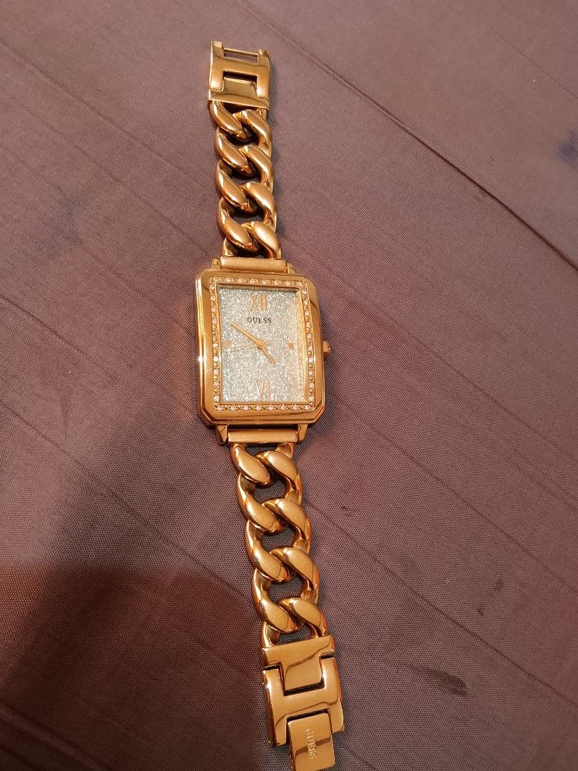 Gold Guess Watch with Rhinestone Face (Category: Women's Watches) located in Manila. Submitted by wildwind_73f77a (Listing ID 1461641512, Image 1). Description: - Gold-tone Guess watch - Rectangular face with a light blue, sparkly dial - Accented with small rhinestones around the face - Chunky chain link strap - Clasp features the Guess logo - Stainless steel back - Perfect statement accessory.
