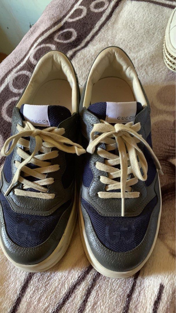 Gucci Interlocking GG Lace Up Sneakers (Category: Sneakers) located in Manila. Submitted by notjaneahe05680 (Listing ID 1462140511, Image 1). Description: - Authentic Gucci sneakers - Navy blue canvas with grey leather accents - Iconic GG logo pattern - Gold Gucci logo on heel - Lace-up closure with cream laces - Chunky sole with Gucci lettering - Ideal for everyday wear.